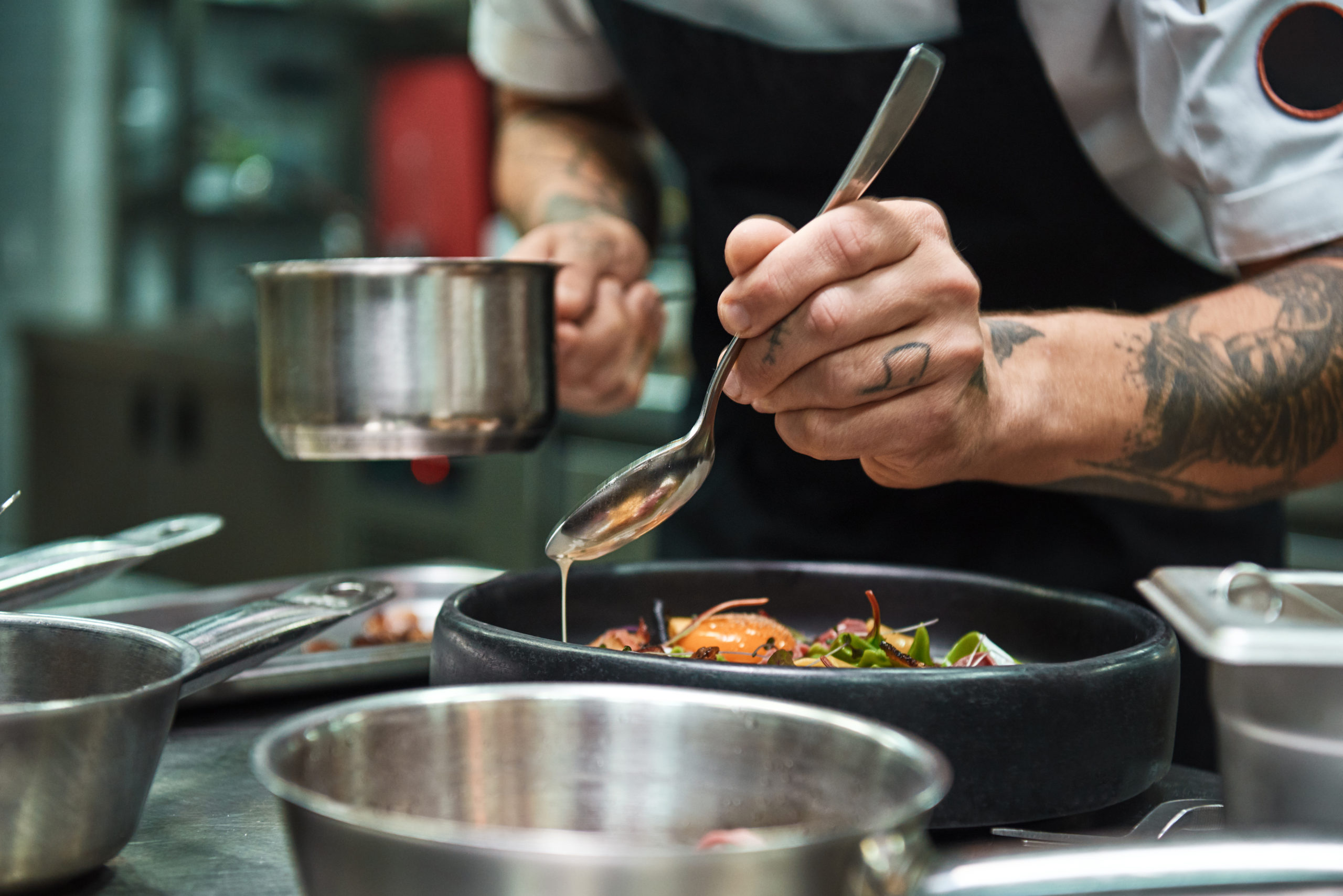 food entrepreneur plating dish with a spoon using a shared kitchen