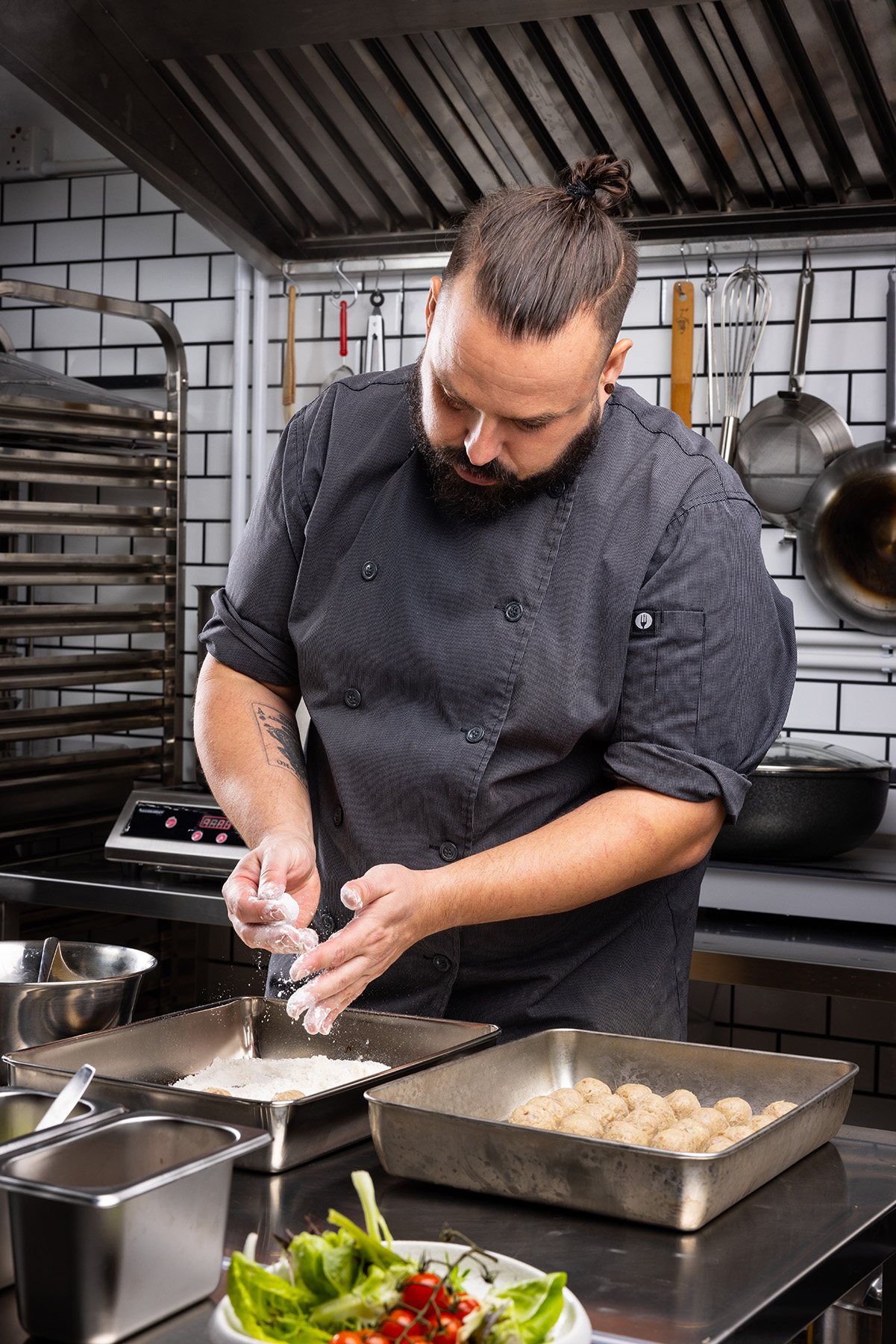 food entrepreneur with tattoos cutting vegetables inside a shared kitchen space